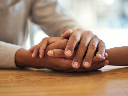 Support, unity and trust by a couple feeling grief due to cancer holding hands together on a table. Closeup of an African American man and woman bonding and connecting due to compassion and love